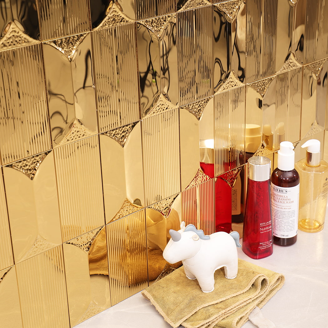 Close side view of gold stainless steel mosaic wall tile near skincare bottles.