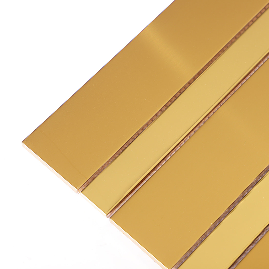 Close-up of brushed and glossy gold stainless steel vertical strip tile surface