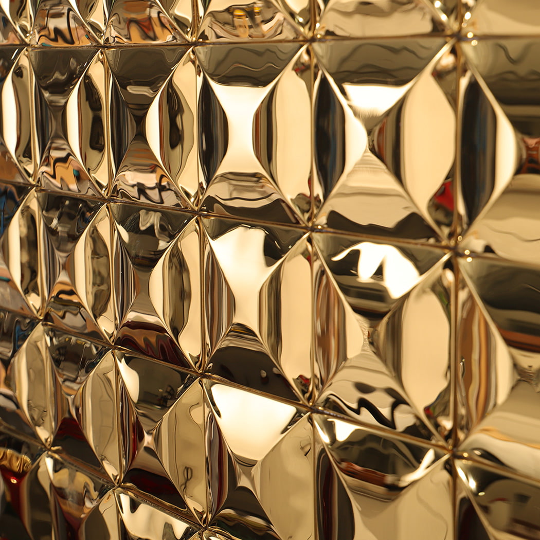 Close-up angle view of gold stainless steel 3D wall tile reflecting light and shadow.
