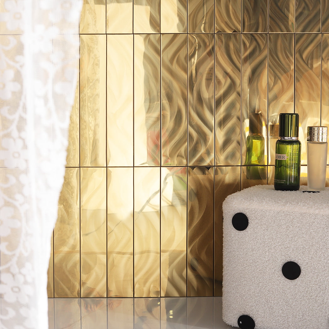 Gold stainless steel wave mosaic wall with skincare bottles and soft lighting.