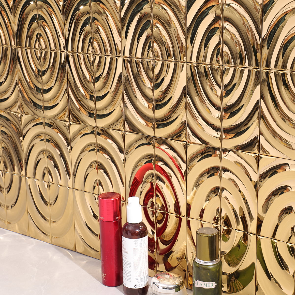 Gold wavy tiles on a wall with various cosmetic products placed in front 