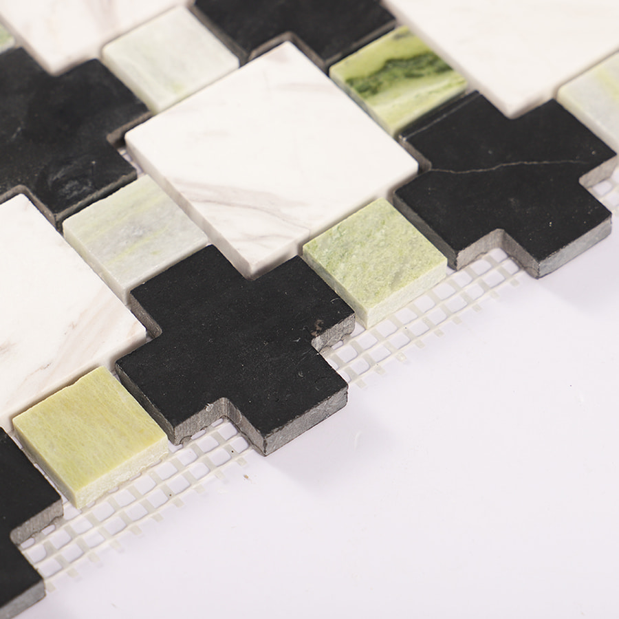Edge detail of green black and white geometric marble mosaic tile with mesh backing.