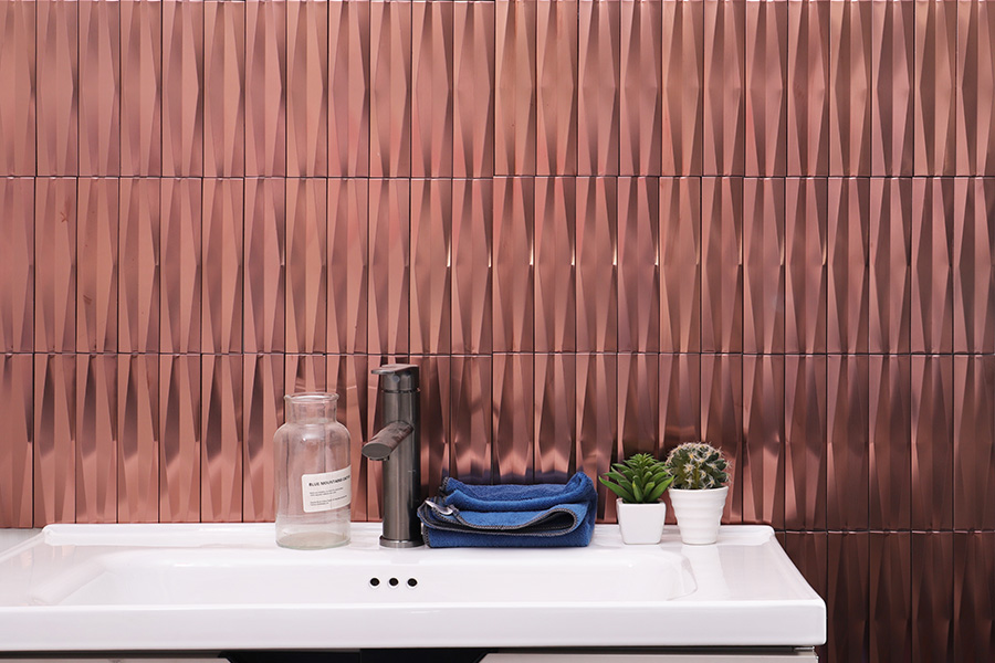 Modern bathroom with copper groutless shower tiles and white sink featuring towels and green plants.