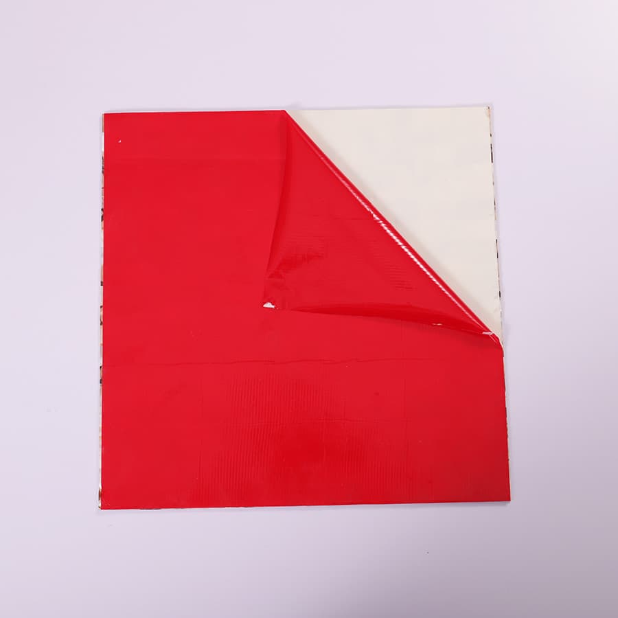 Backside of shell mosaic tile with red peel-and-stick adhesive layer