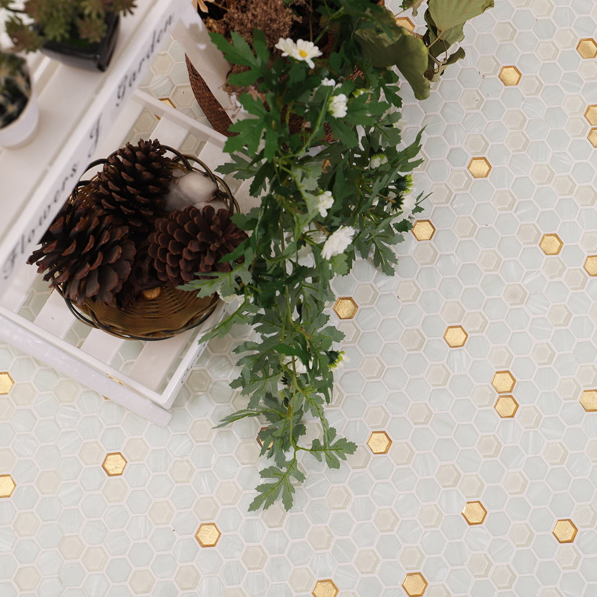 White and gold hex tile floor styled with pinecones and flowers