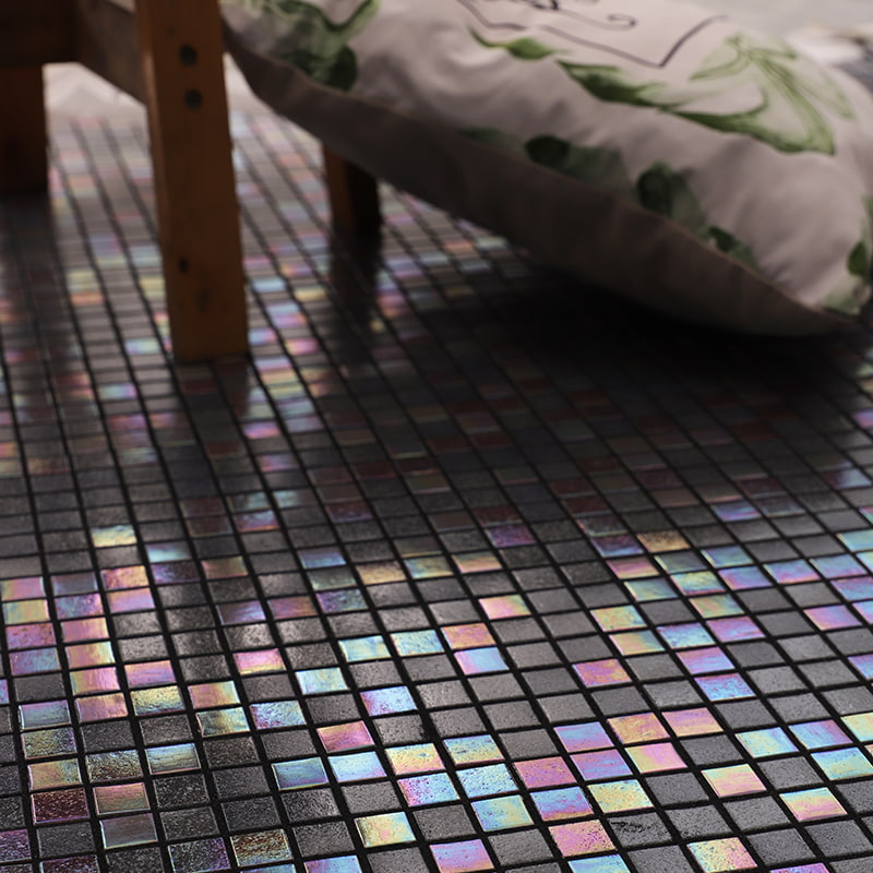 Iridescent square mosaic tiles on matte black floor surface