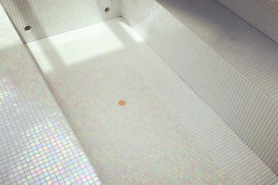 White iridescent pool tiles reflecting soft natural light, creating a beautiful ambiance 