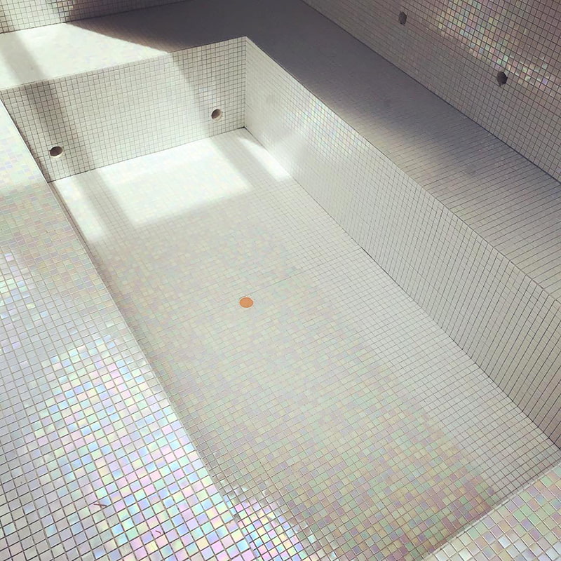 Shimmering iridescent white pool tiles reflecting light for a sparkling pool finish