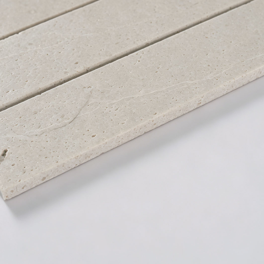 Angled close-up showing the porous surface and thickness of ivory travertine strips
