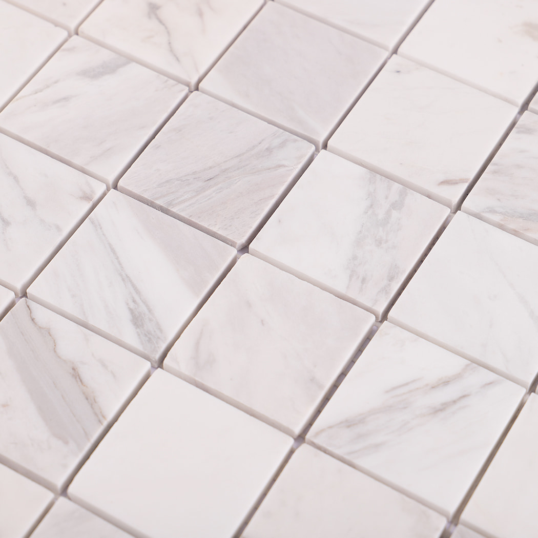 Diagonal close-up highlighting natural grey veining of Jazz White marble tiles.
