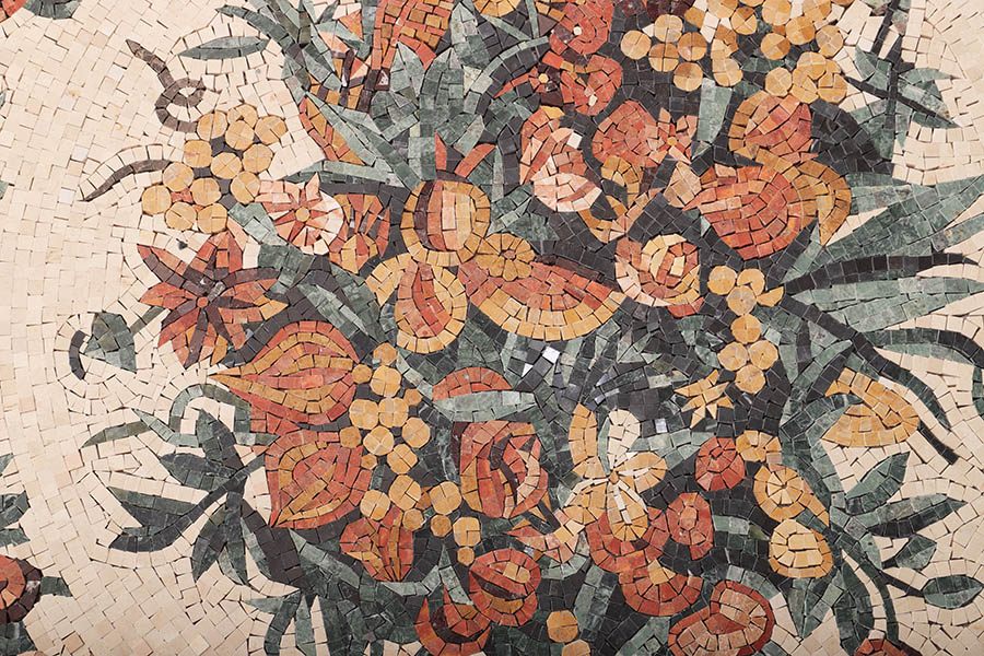 Large floral stone mosaic mural panel with green leaves and warm flower patterns