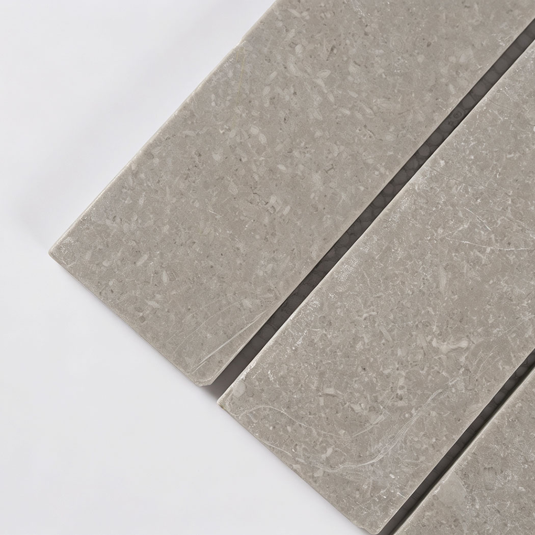 Close-up of light gray marble strips with fine fossil patterns and soft veining