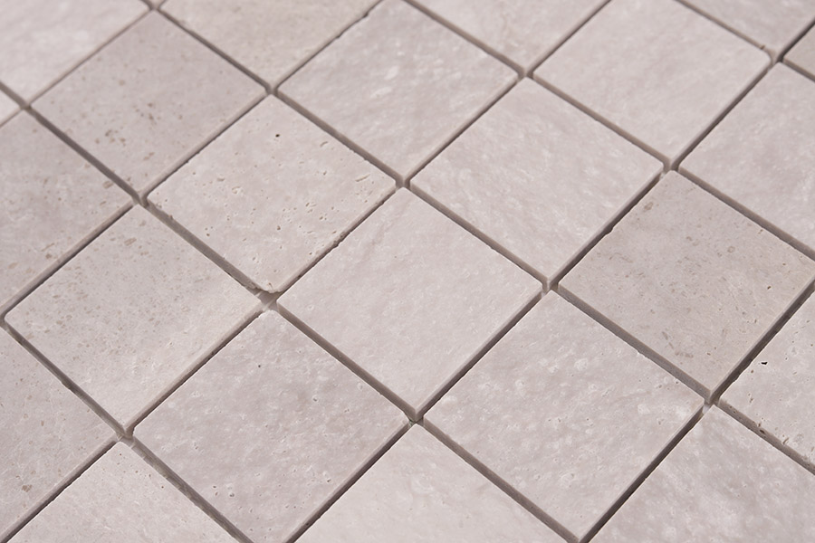 Close-up of light gray tiles in a marble square mosaic showing natural stone texture.