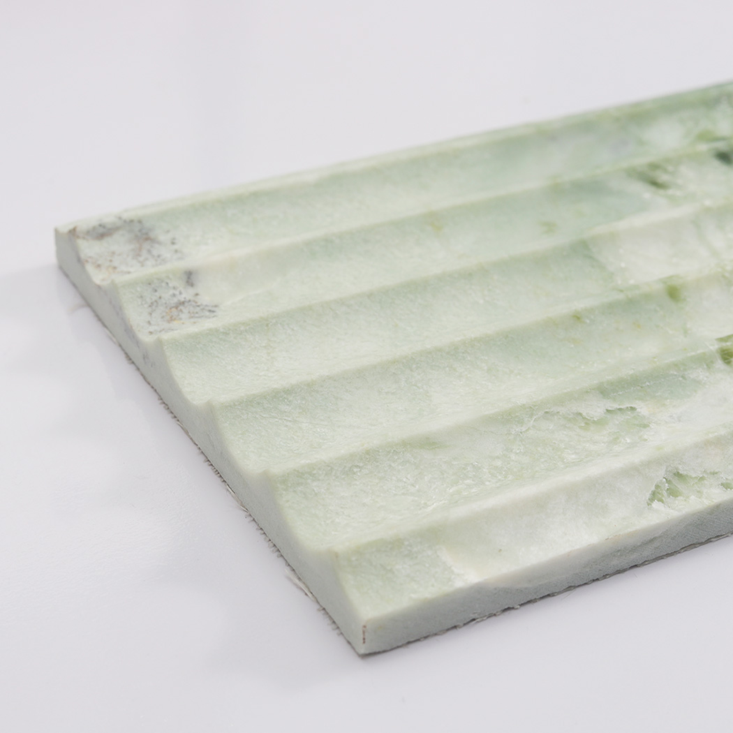 Edge detail of light green marble fluted tile with raised linear grooves