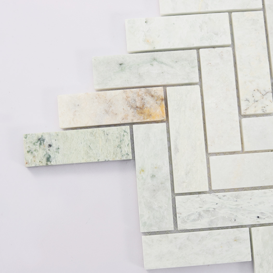 Close up of light green marble herringbone mosaic tile edge detail