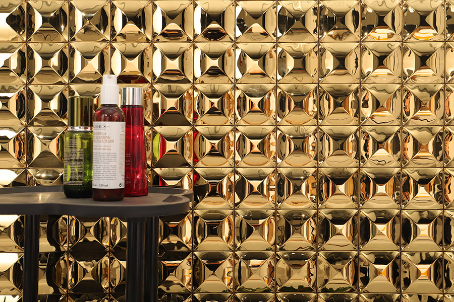 A wide landscape view of polished gold 3D tiles with a sharp geometric pyramid design.