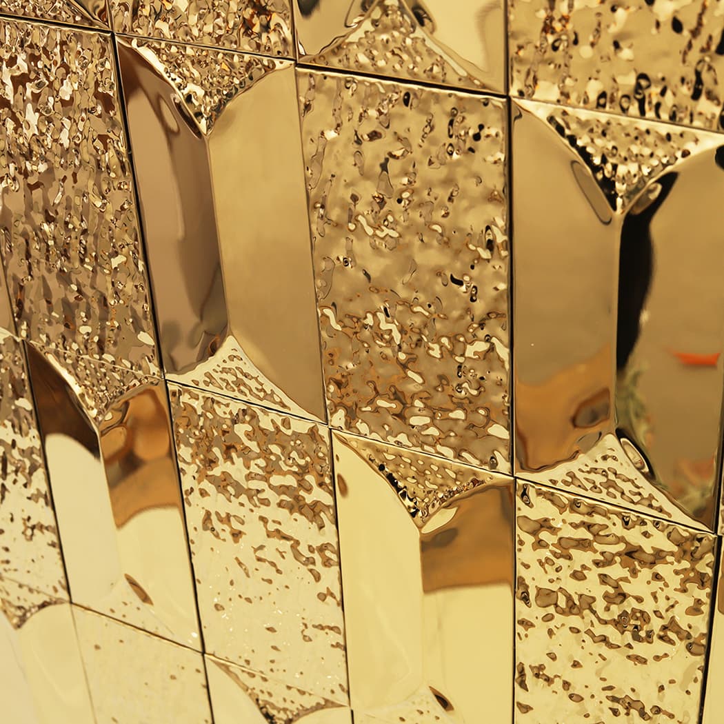 An angled close up of luxury gold tiles with a textured and reflective finish.