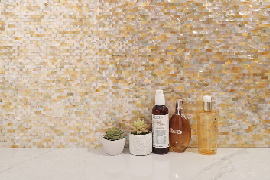 Beige shell mosaic wall tile with toiletries on a bathroom vanity