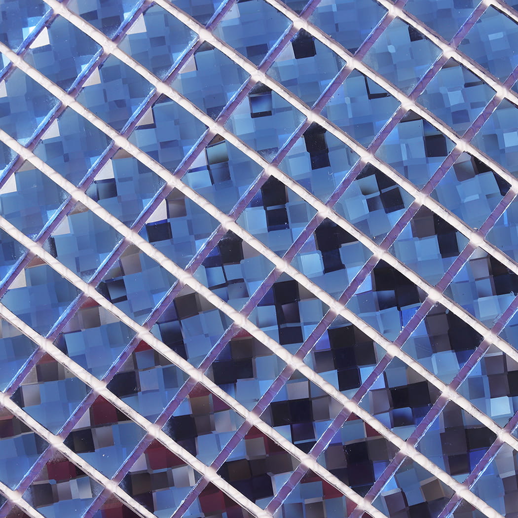 Macro detail of blue mirror glass mosaic tiles showing intricate reflective facets.
