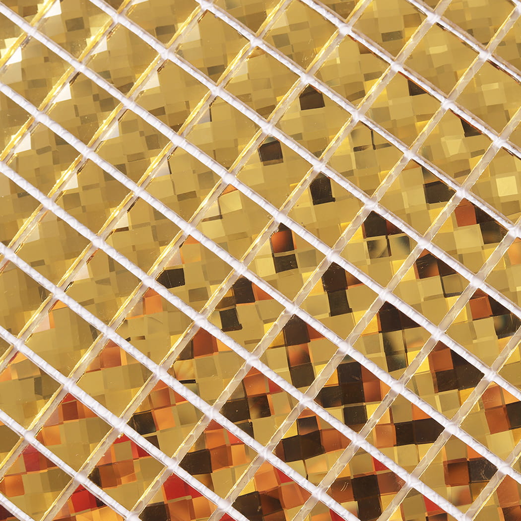 Macro detail of gold mirror glass mosaic tiles showing intricate reflective facets.