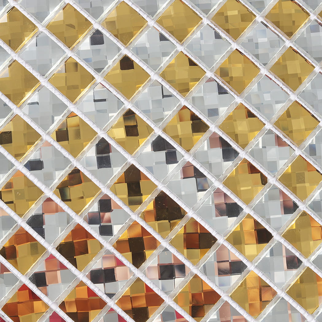 Macro detail of gold and silver beveled glass mosaic showing reflective facets.