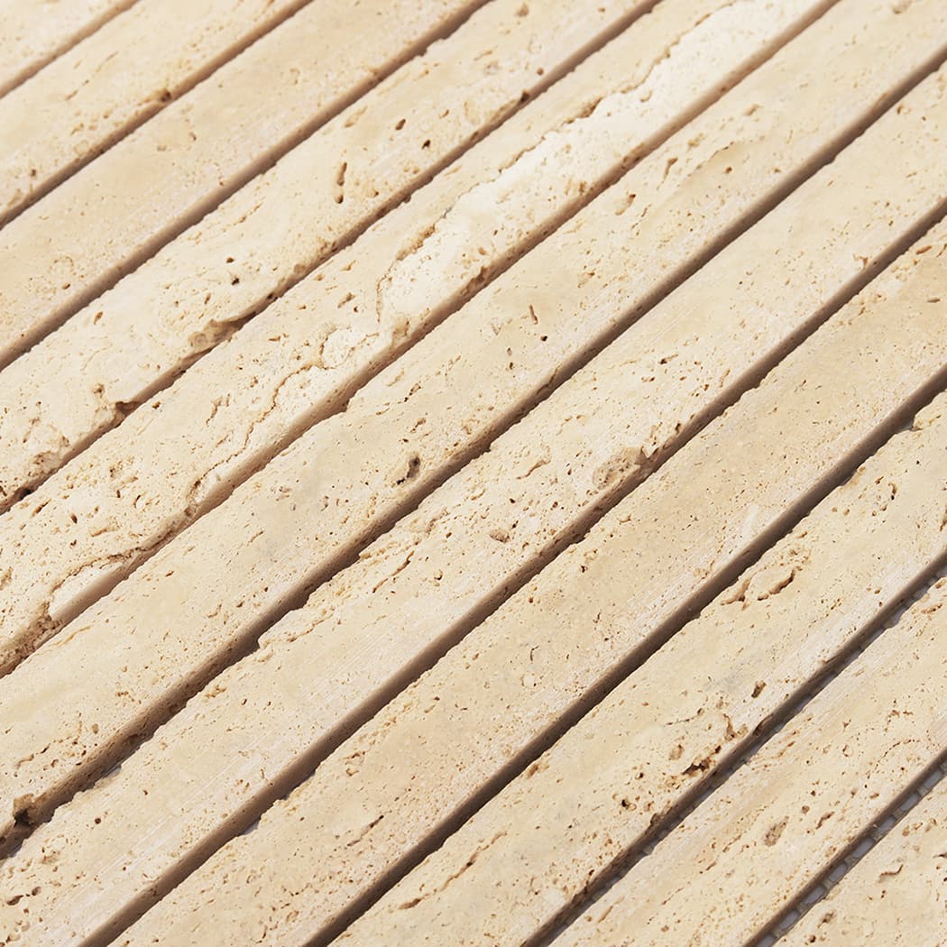 Macro shot of the rounded edges and natural color variations in beige travertine mosaic strips.