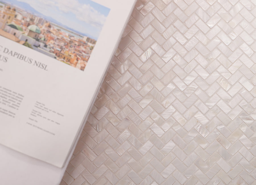 Open magazine laid atop a pearl shell herringbone mosaic tile surface