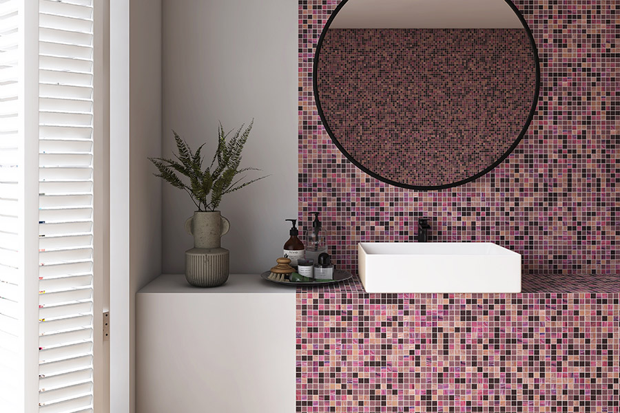 Close-up of Mauve Tiles square glass mosaic backsplash behind a round mirror in a luxury bathroom.