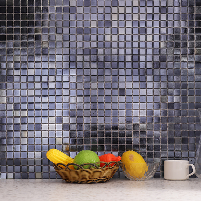 Black flash metallic mosaic wall tiles on a wall, with fruits displayed in front.