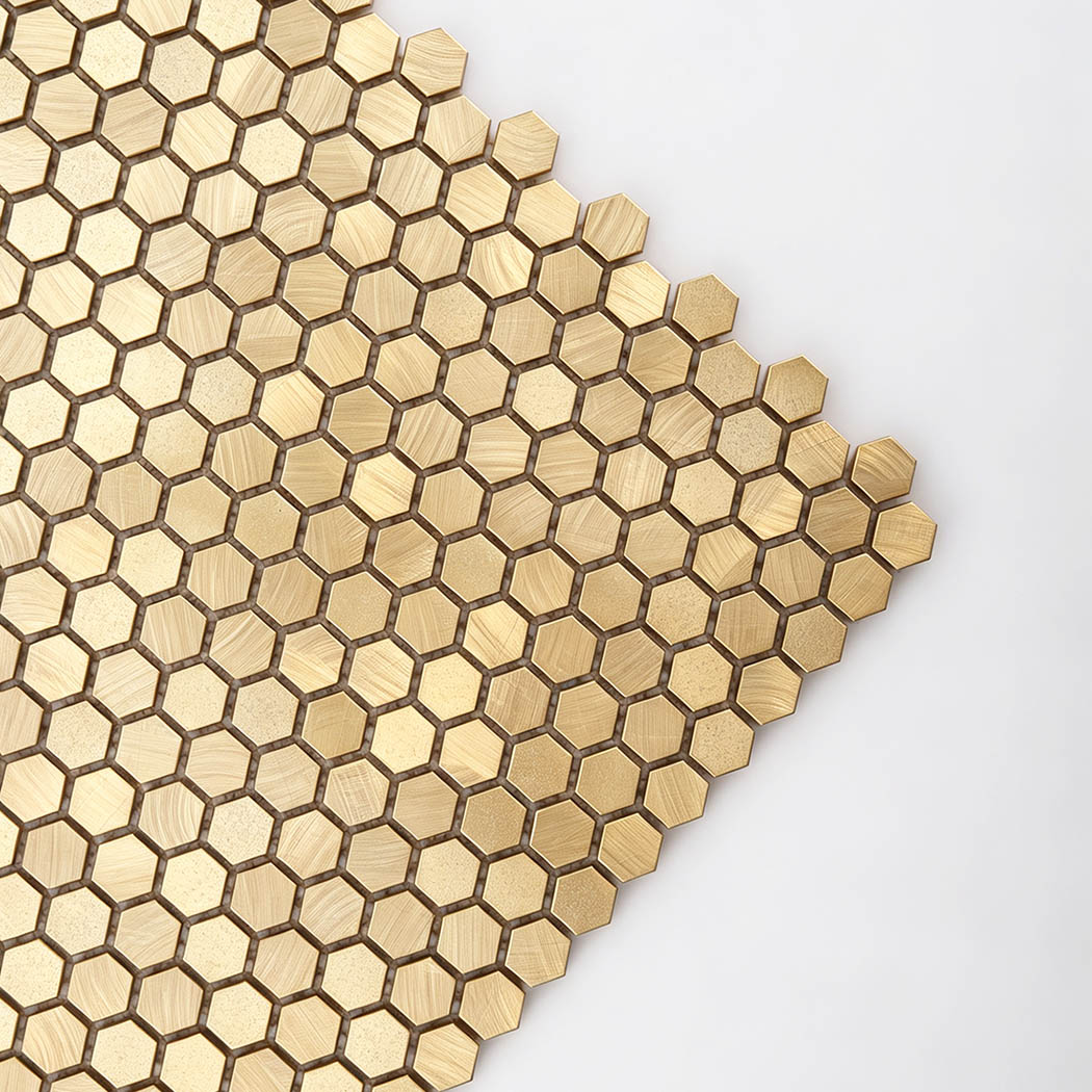 Close up of metallic brushed finish on mini gold hexagon aluminum wall tile