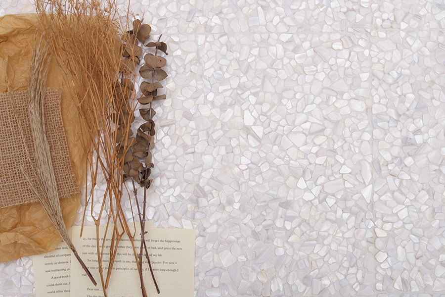 Flatlay of white mini pebble tiles with natural shell texture and dried floral decor