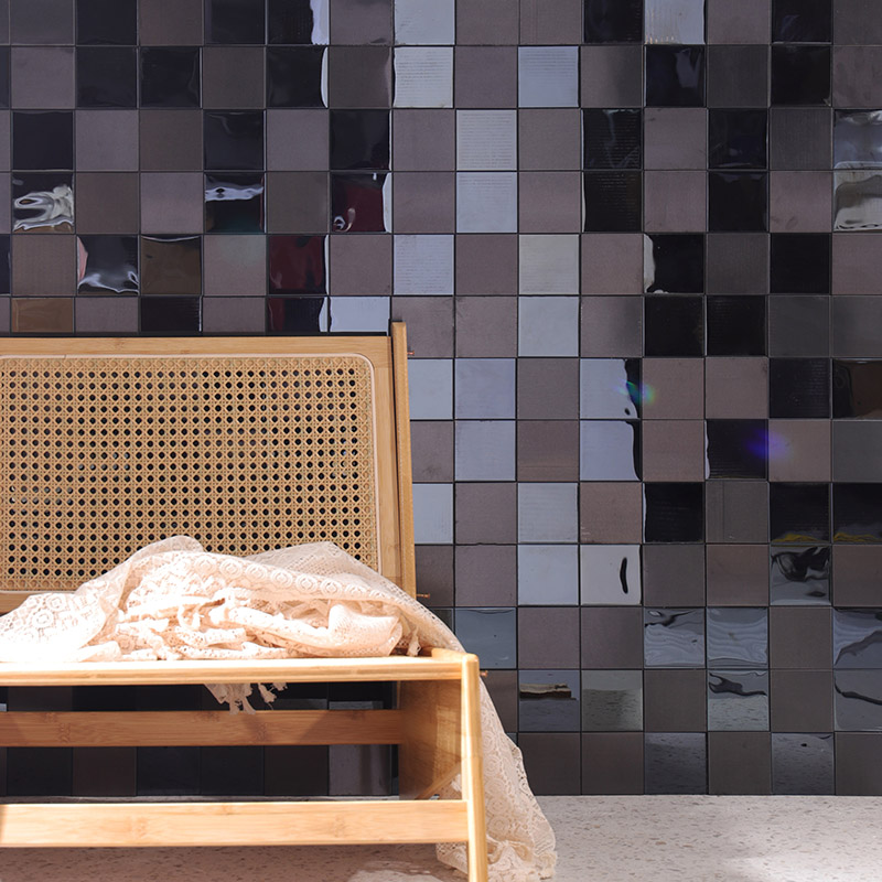 Modern mixed-finish black and grey large square tiles wall with a rattan chair.