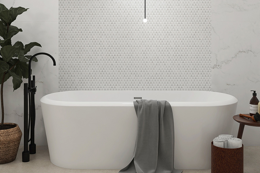 Modern bathroom with white tub and geometric wall tiles in a minimalist interior design.