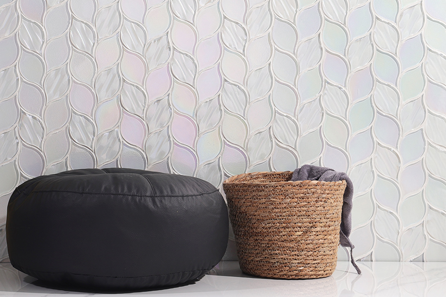 Stylish room with leaf-pattern iridescent tiles, pouf, and woven basket.