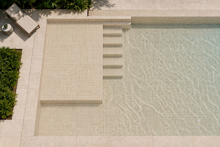 Overhead view of beige travertine pool tiles in a modern outdoor swimming pool