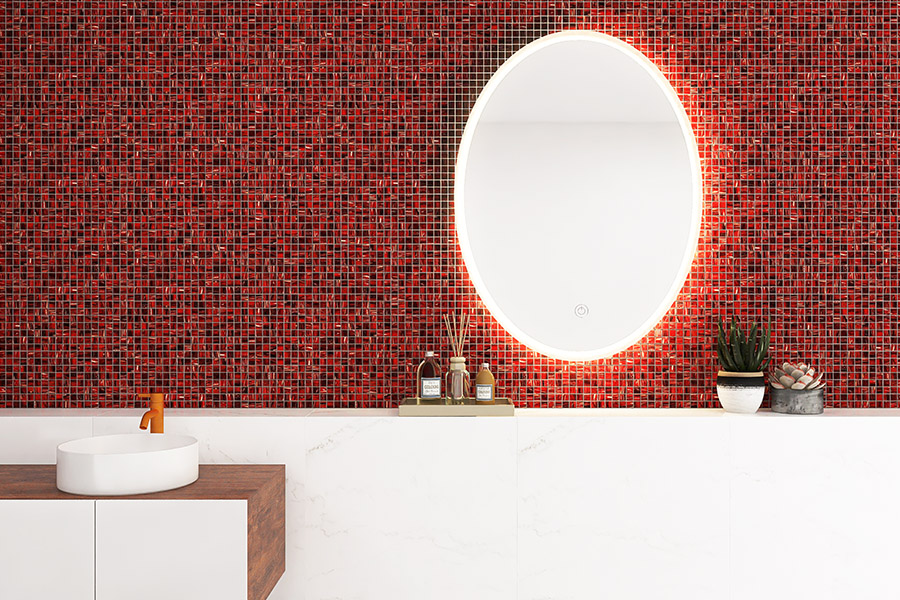 Modern red backsplash tiles behind a white bathroom vanity with sleek fixtures.