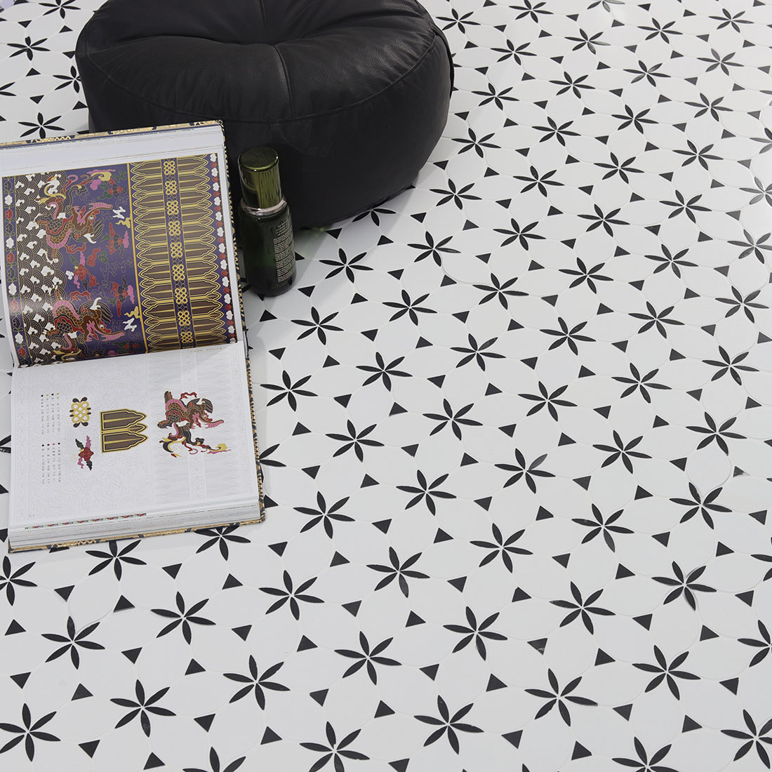 Black and white floral tile floor with an open book, small bottle, and black beanbag chair.