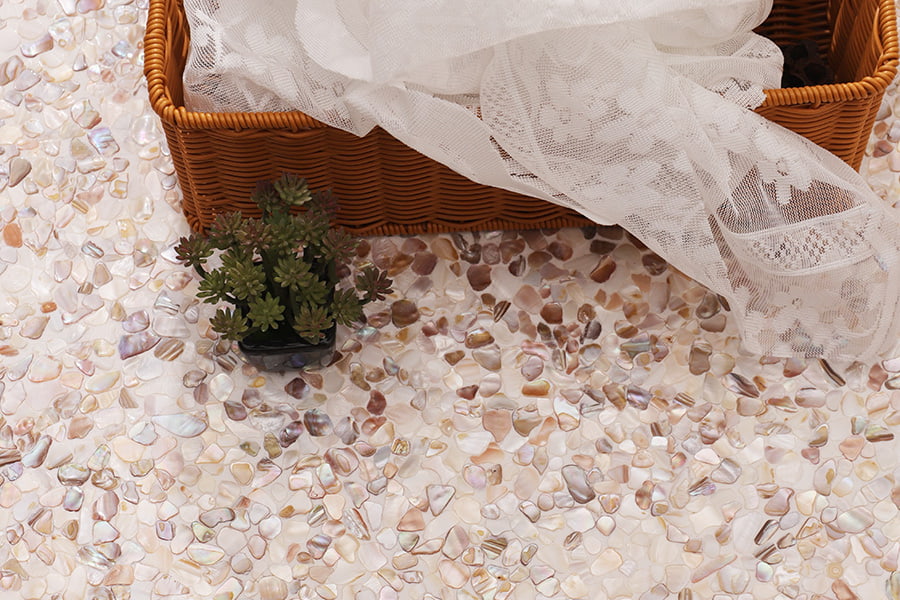 Close-up of natural shell pebble tiles with succulent and wicker basket