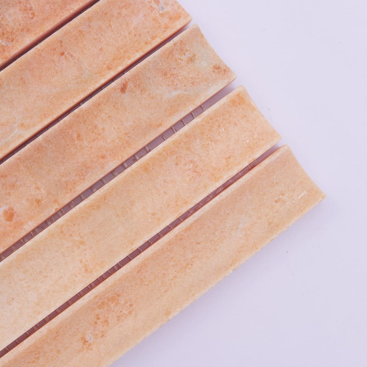 Corner close-up of orange fluted marble tile strips