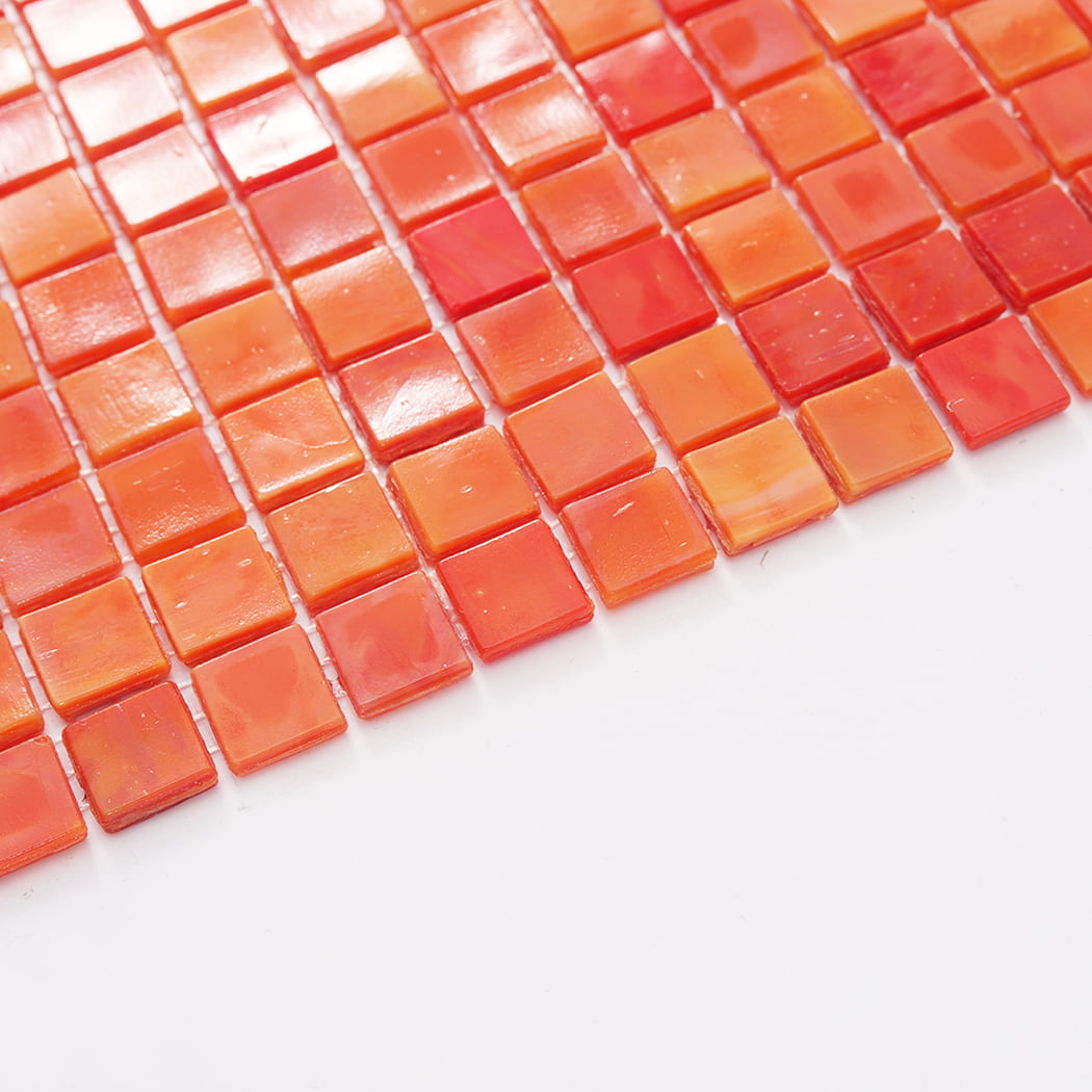 Edge view of orange mixed square glass mosaic tile sheet on a white background