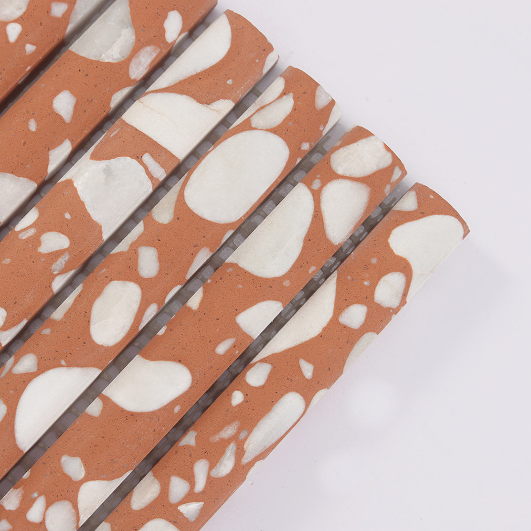 Corner close-up of orange terrazzo fluted tile with large white stone chips