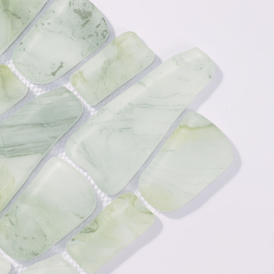 Close-up of pale green irregular glass mosaic tile pieces on mesh backing