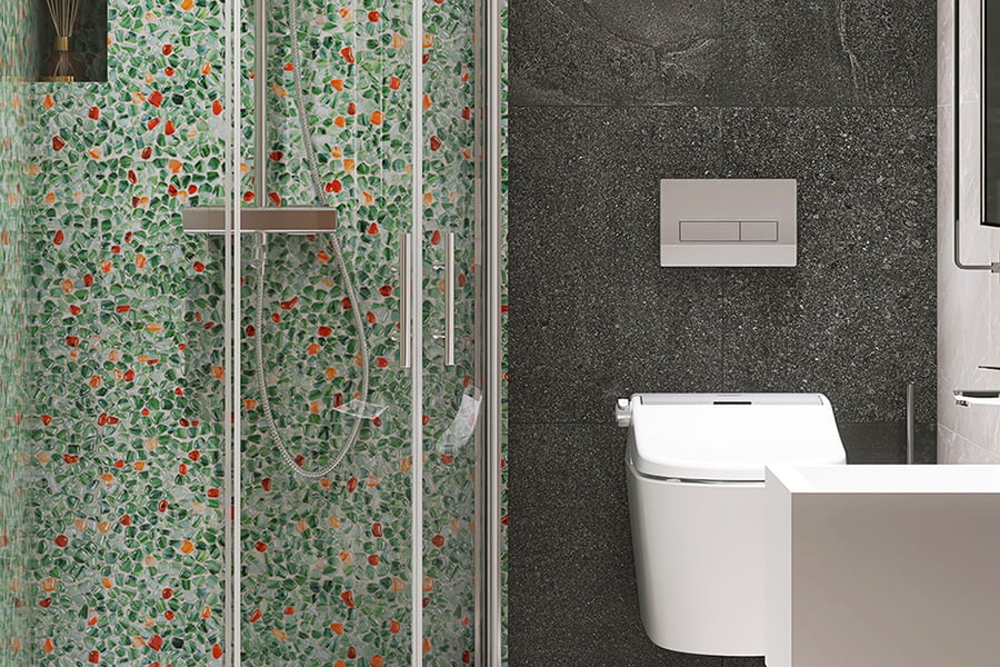 Pebble wall tiles in green and red tones in a glass shower