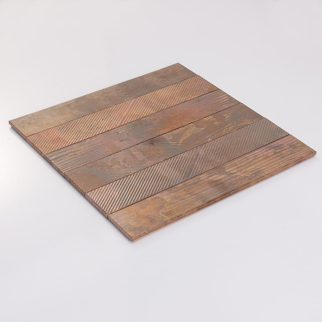 An angled view of a square copper-colored tile sheet laying flat on a white surface.