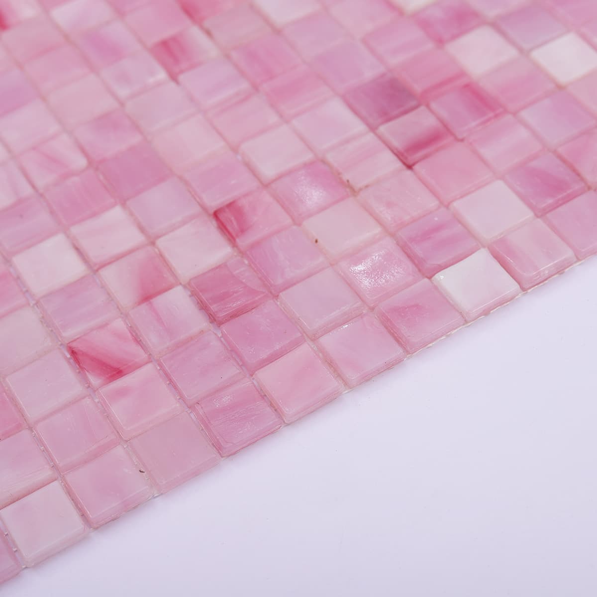 Detailed side view of pink glass mosaic tiles revealing surface reflection and finish