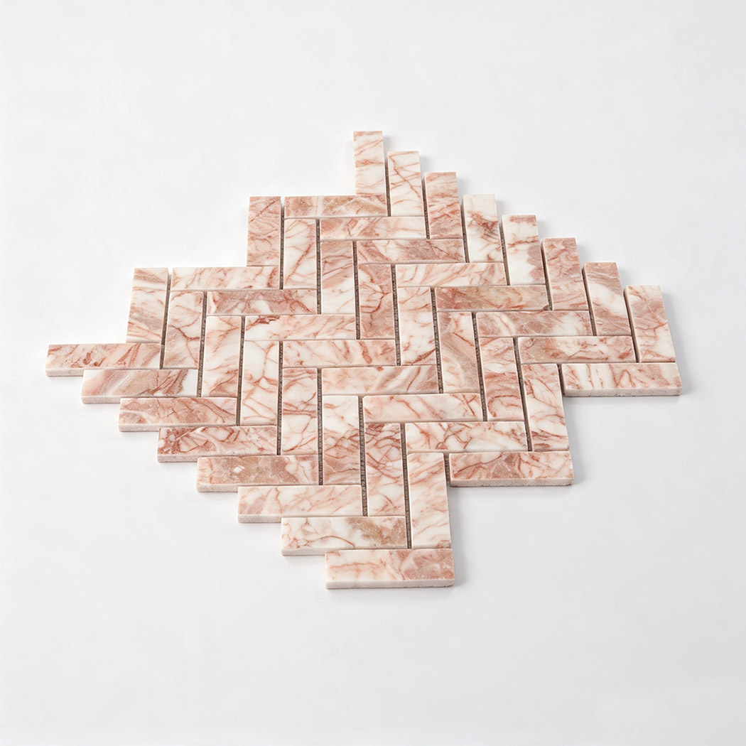 Angled view of pink and white veined marble mosaic in a herringbone pattern