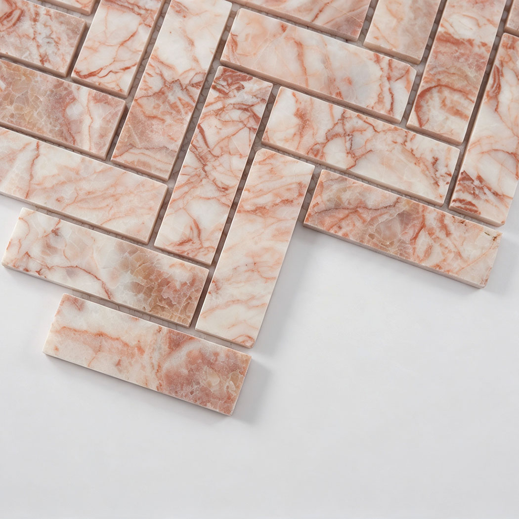 Close-up of pink and white veined marble pieces in a herringbone mosaic