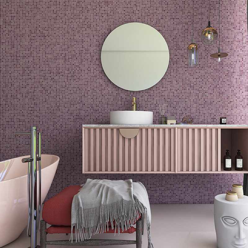 Round mirror and sink against a purple mosaic tile wall with gold foil backing 