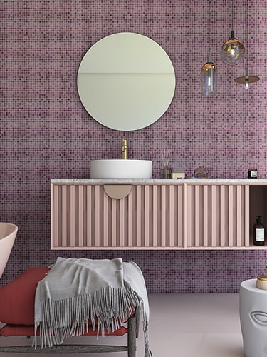 Bathroom vanity and towel against a purple mosaic tile wall with gold foil backing 
