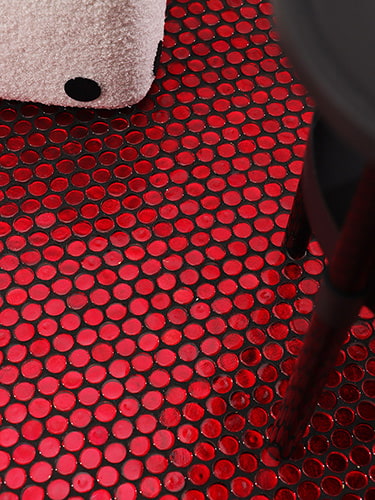 Glossy red glass penny tile floor with black side table leg 